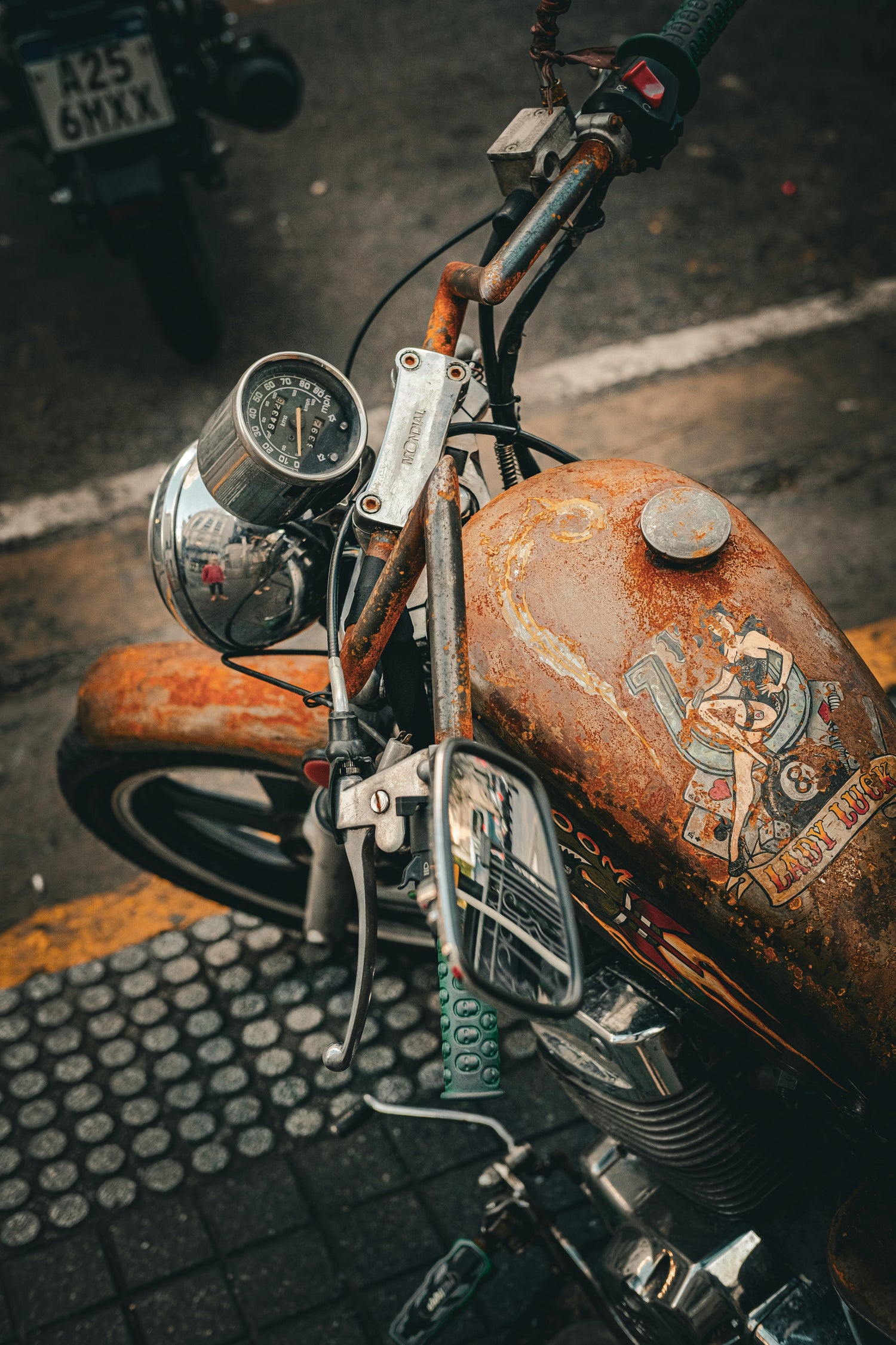 Rust-covered motorcycle with detailed artwork on a street.