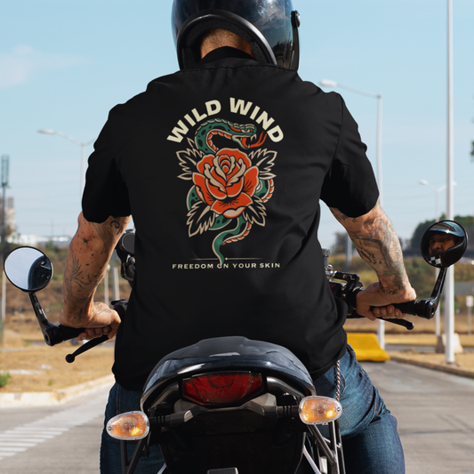 Person riding a motorcycle wearing a black t-shirt with a snake and rose design and 'Wild Wind' text.