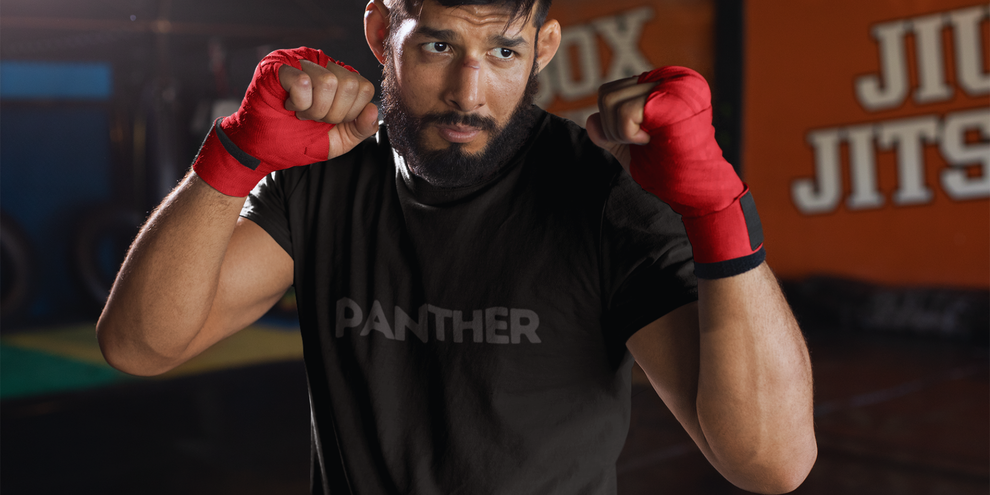 Person wearing red boxing gloves and a black 'Panther' shirt in a gym setting.
